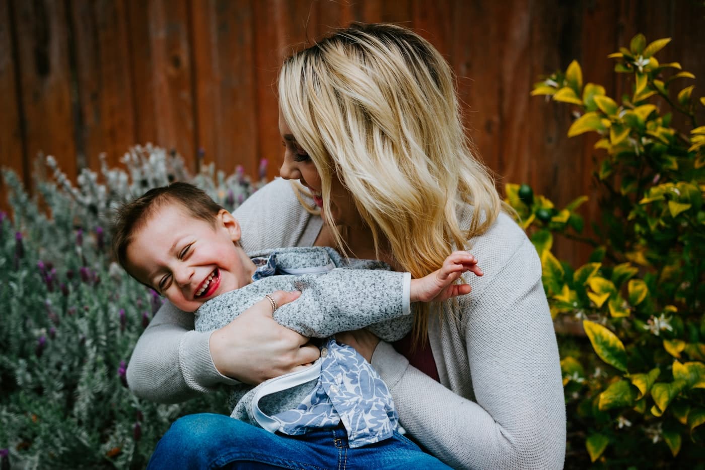 A mother laughing with her young daughter outdoors